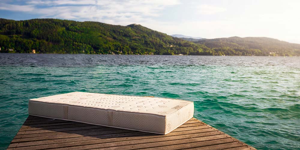 Eine Matratze liegt auf einer Holzplattform vor einem Meer